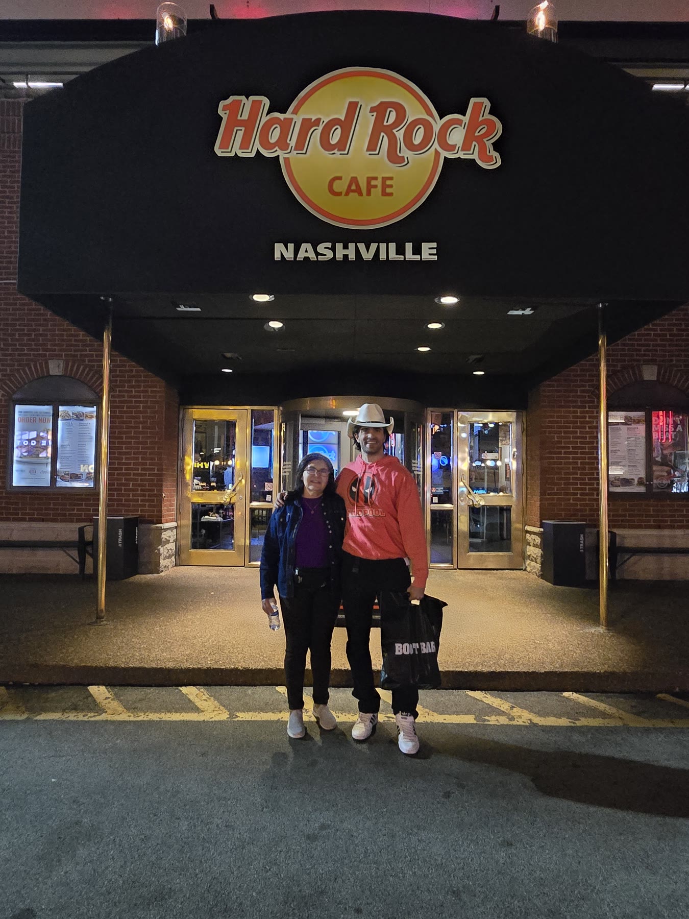 Gigio Teixeira com a mãe diante do Hard Rock Cafe Nashville à noite