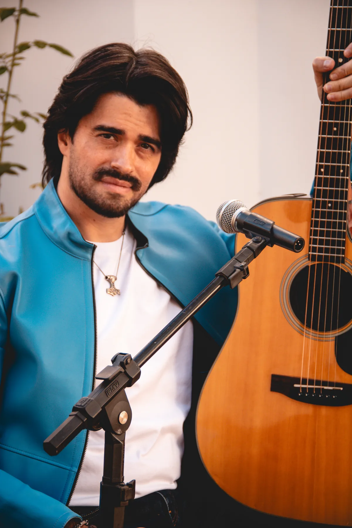 Retrato atual de Gigio Teixeira com o violão diante do microfone