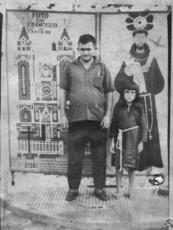 Homem e criança diante de um painel de São Francisco em retrato de família